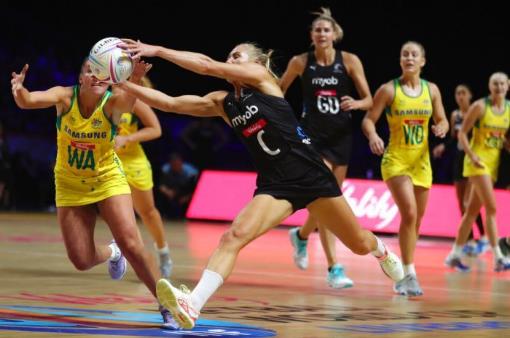 Netballers lunge for the ball during a contest